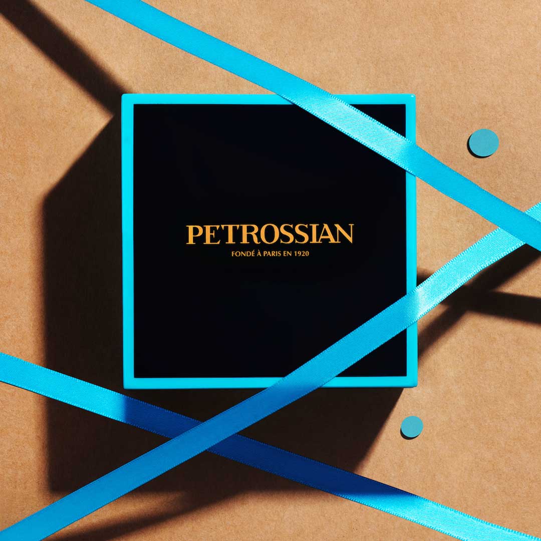 a navy blue box with teal accents, sitting on brown wrapping paper with teal-blue ribbons